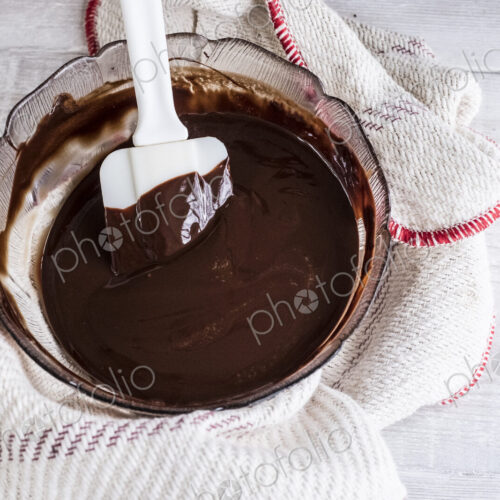 A bowl of chocolate brownie ingredients being stirred by a spatula.