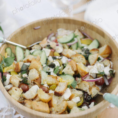 A bowl of mixed salad on a table in a garden.