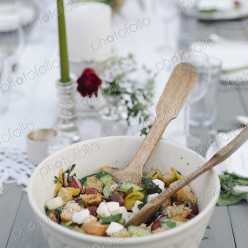 A bowl of salad on a table in a garden.