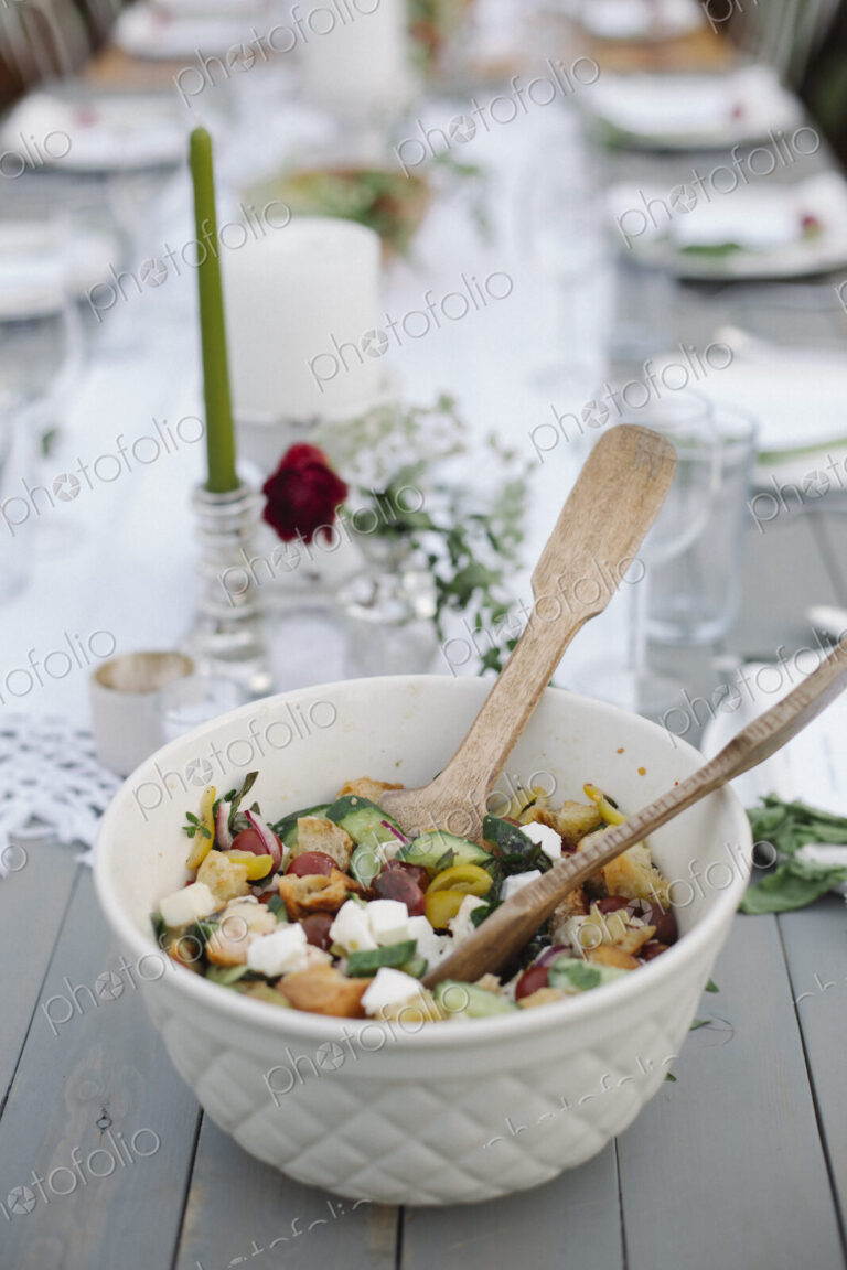 A bowl of salad on a table in a garden.