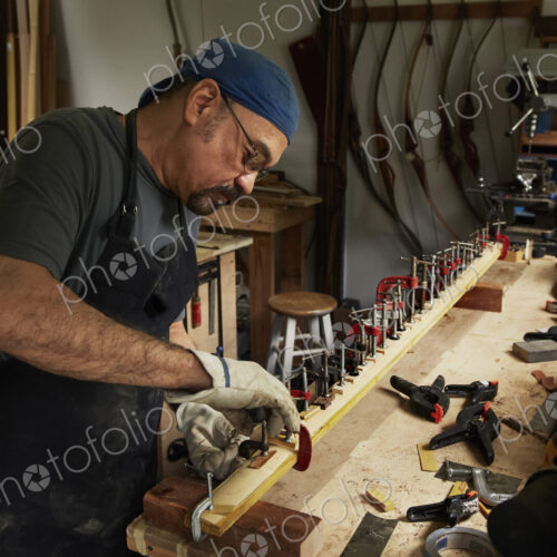 A bowman, a skilled man making a bow, in his workshop.