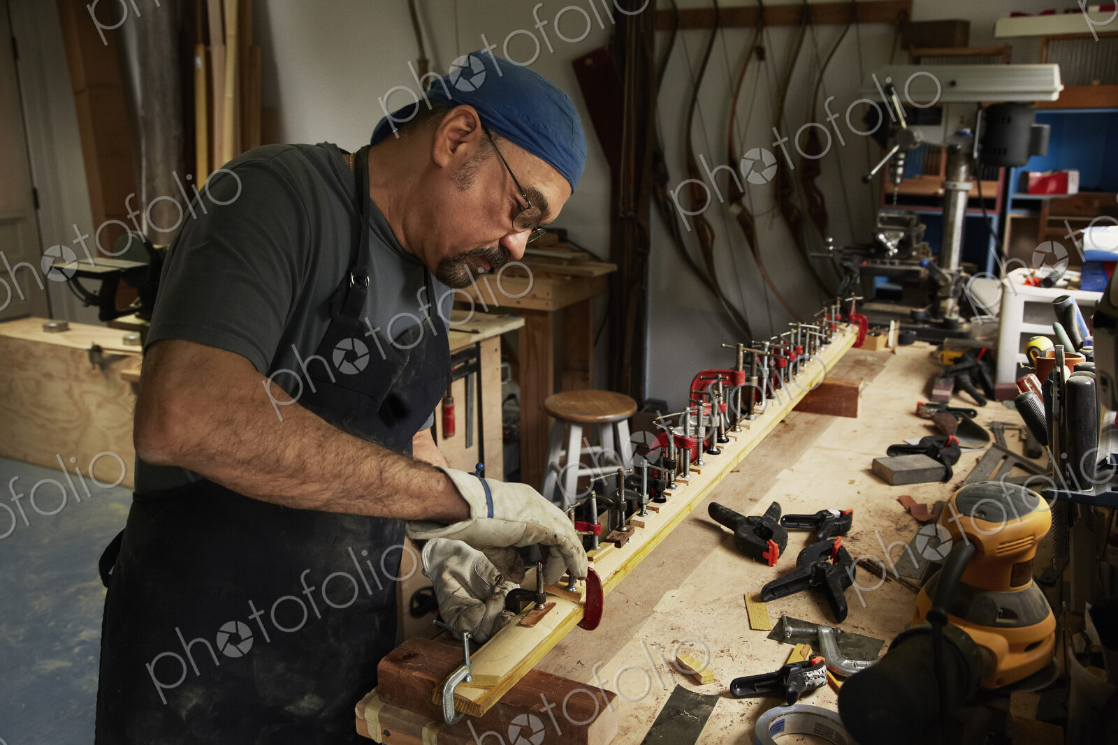 A bowman, a skilled man making a bow, in his workshop.