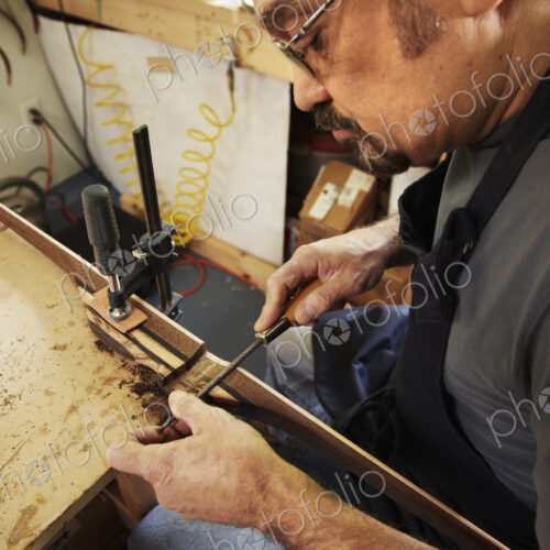 A bowman, a skilled man making a bow, in his workshop.