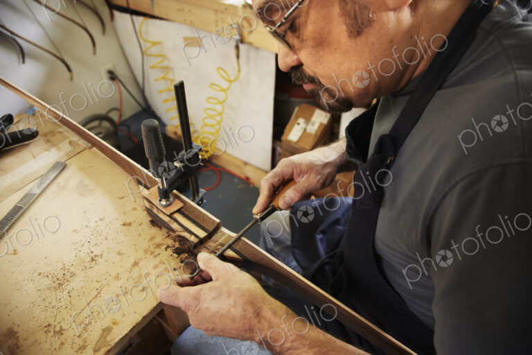 A bowman, a skilled man making a bow, in his workshop.