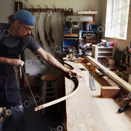 A bowman, a skilled man making a bow, in his workshop.