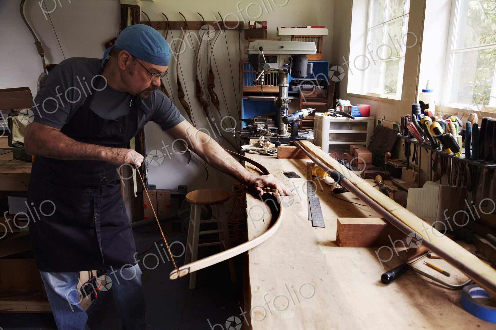 A bowman, a skilled man making a bow, in his workshop.
