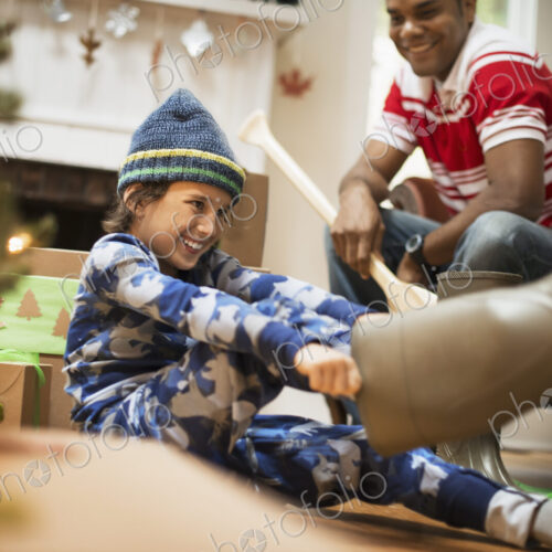 A boy by a Christmas tree unwrapping a gift, and trying on muck boots. A boy by a Christmas tree unwrapping a gift, and trying on muck boots.