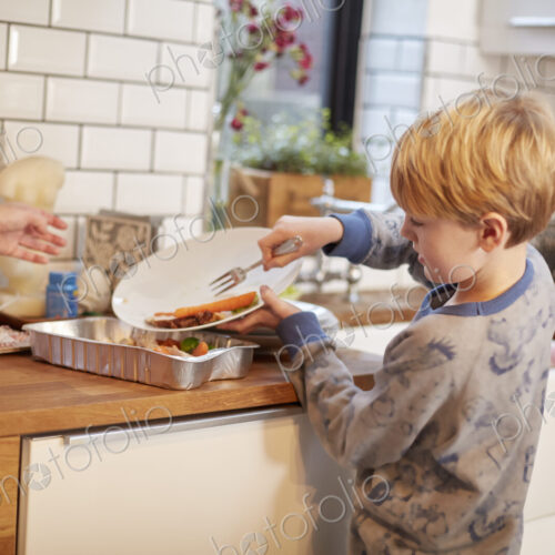 A boy clearing a plate after a meal.