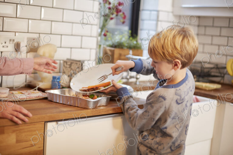 A boy clearing a plate after a meal.