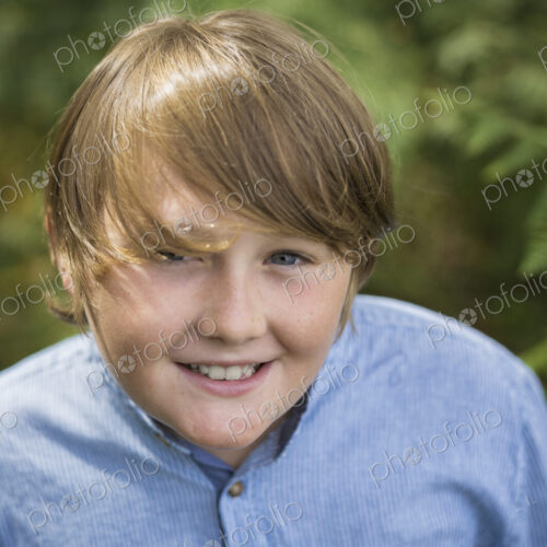 A boy in a denim button down shirt looking up at the camera. A boy in a denim button down shirt looking up at the camera.