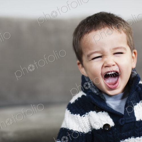 A boy in a striped shirt opening his mouth wide. A boy in a striped shirt opening his mouth wide.