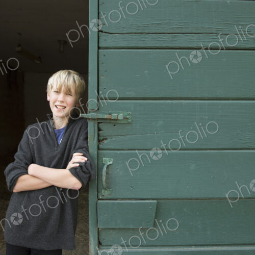 A boy leaning against a wooden barn door, at an animal sanctuary. A boy leaning against a wooden barn door, at an animal sanctuary.