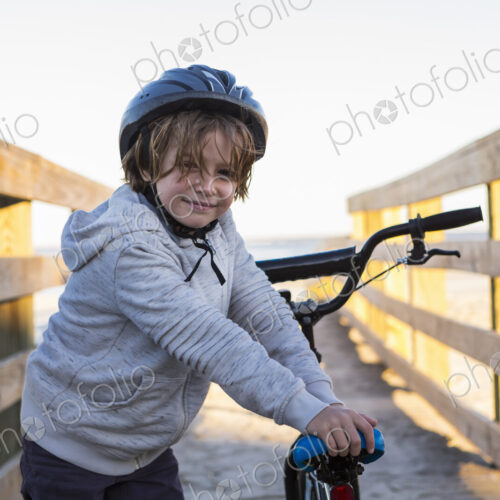 A boy on a bicycle, with helmet on a walkway on the beach, St. Simon's Island, Georgia