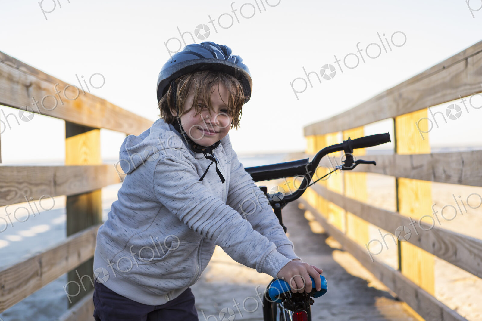 A boy on a bicycle, with helmet on a walkway on the beach, St. Simon’s Island, Georgia