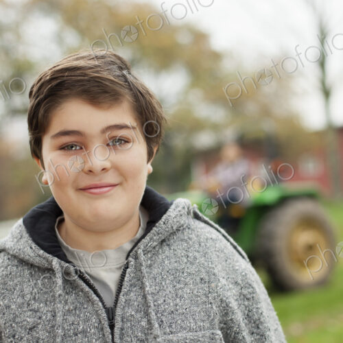 A boy on an organic farm beside a small tractor. A boy on an organic farm beside a small tractor.