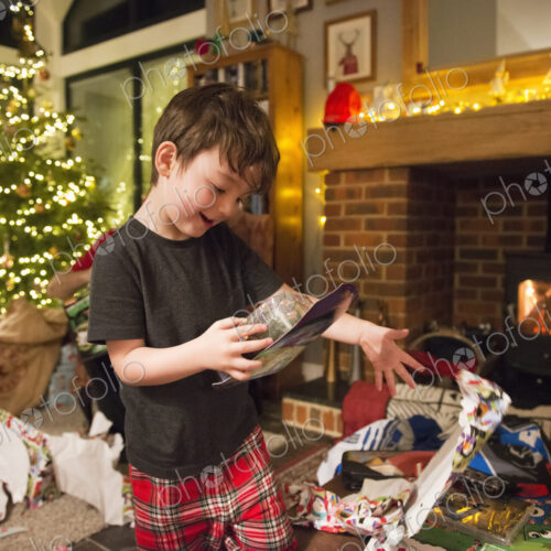 A boy opening his presents on Christmas Day throwing the wrapping paper to the floor.