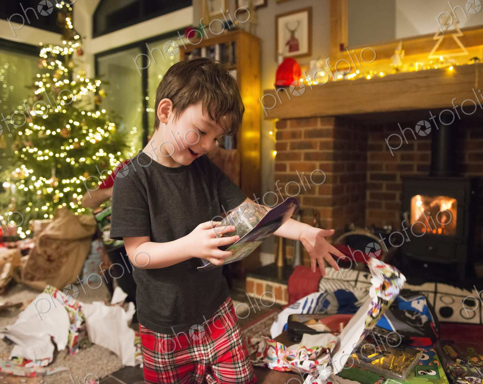 A boy opening his presents on Christmas Day throwing the wrapping paper to the floor.
