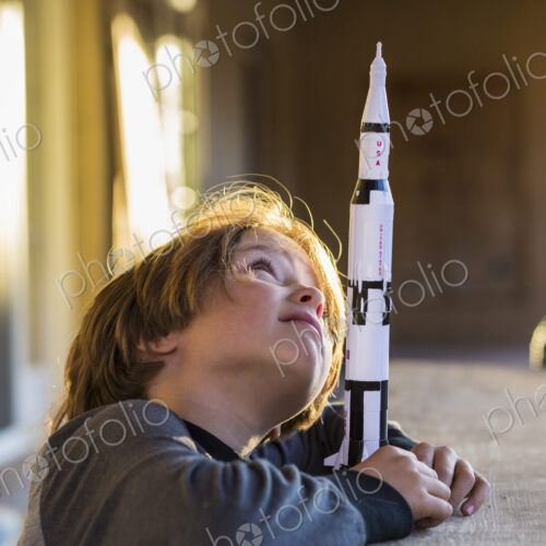 A boy playing with a toy Nasa Saturn 5 rocket, day dreaming about space flight. A boy playing with a toy Nasa Saturn 5 rocket, day dreaming about space flight.