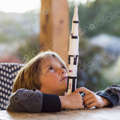 A boy playing with a toy Nasa Saturn 5 rocket, day dreaming about space flight. A boy playing with a toy Nasa Saturn 5 rocket, day dreaming about space flight.