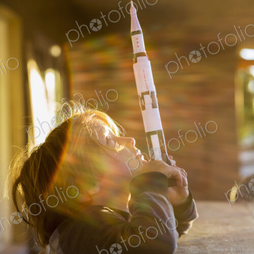 A boy playing with a toy Nasa Saturn 5 rocket, day dreaming about space flight. A boy playing with a toy Nasa Saturn 5 rocket, day dreaming about space flight.