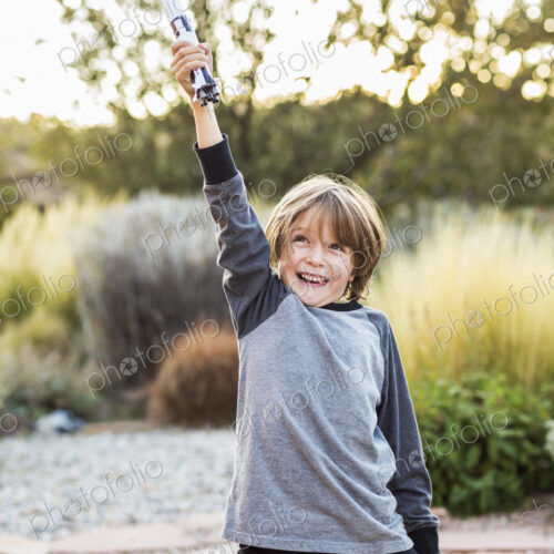 A boy playing with a toy Nasa Saturn 5 rocket, holding it above his head. A boy playing with a toy Nasa Saturn 5 rocket, holding it above his head.