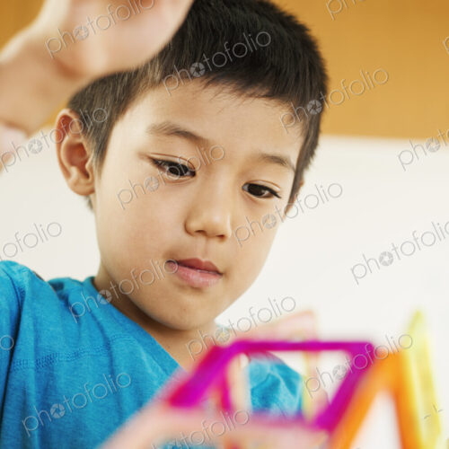A boy playing with coloured geometric shapes.