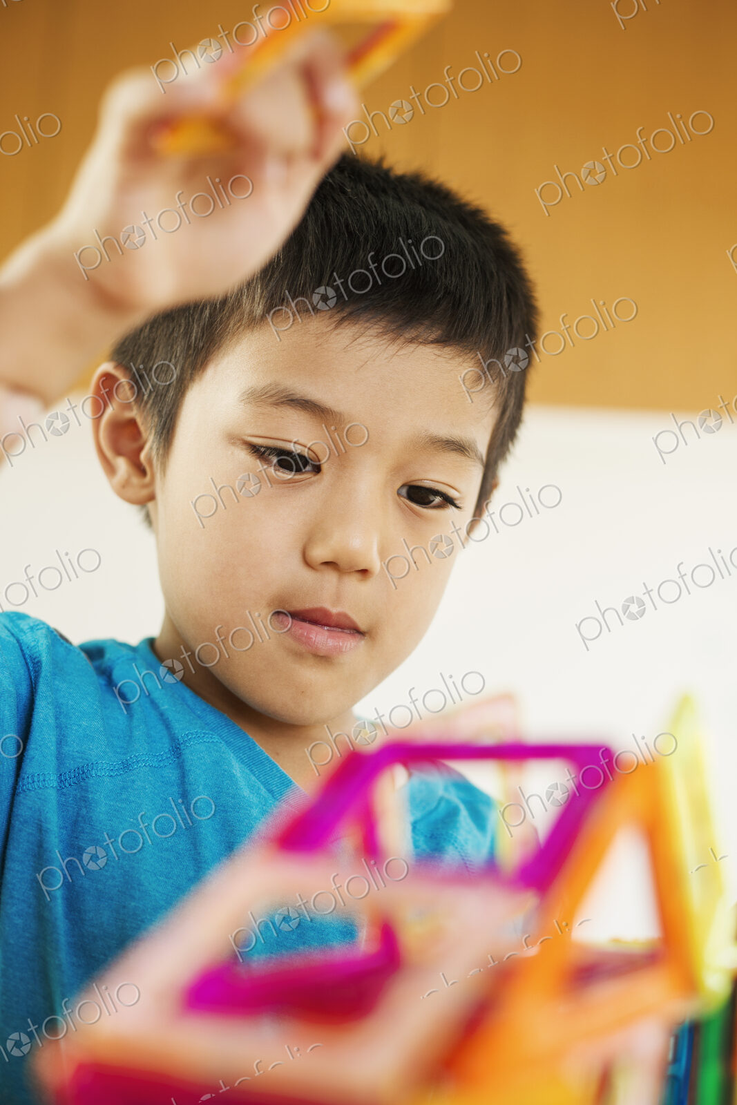 A boy playing with coloured geometric shapes.