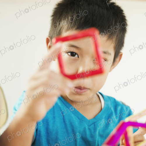 A boy playing with coloured geometric shapes.
