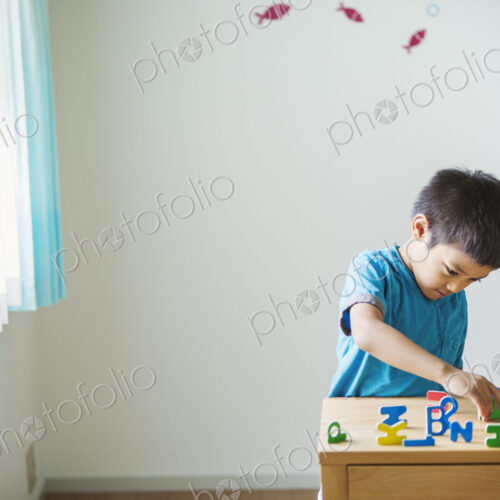 A boy playing with colourful alphabet letters.