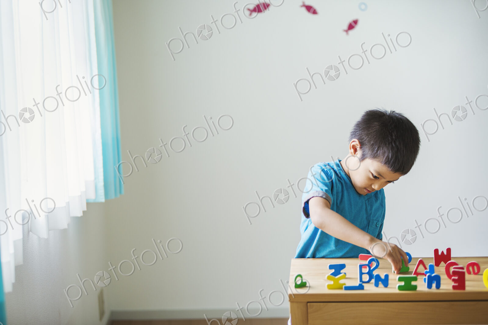 A boy playing with colourful alphabet letters.