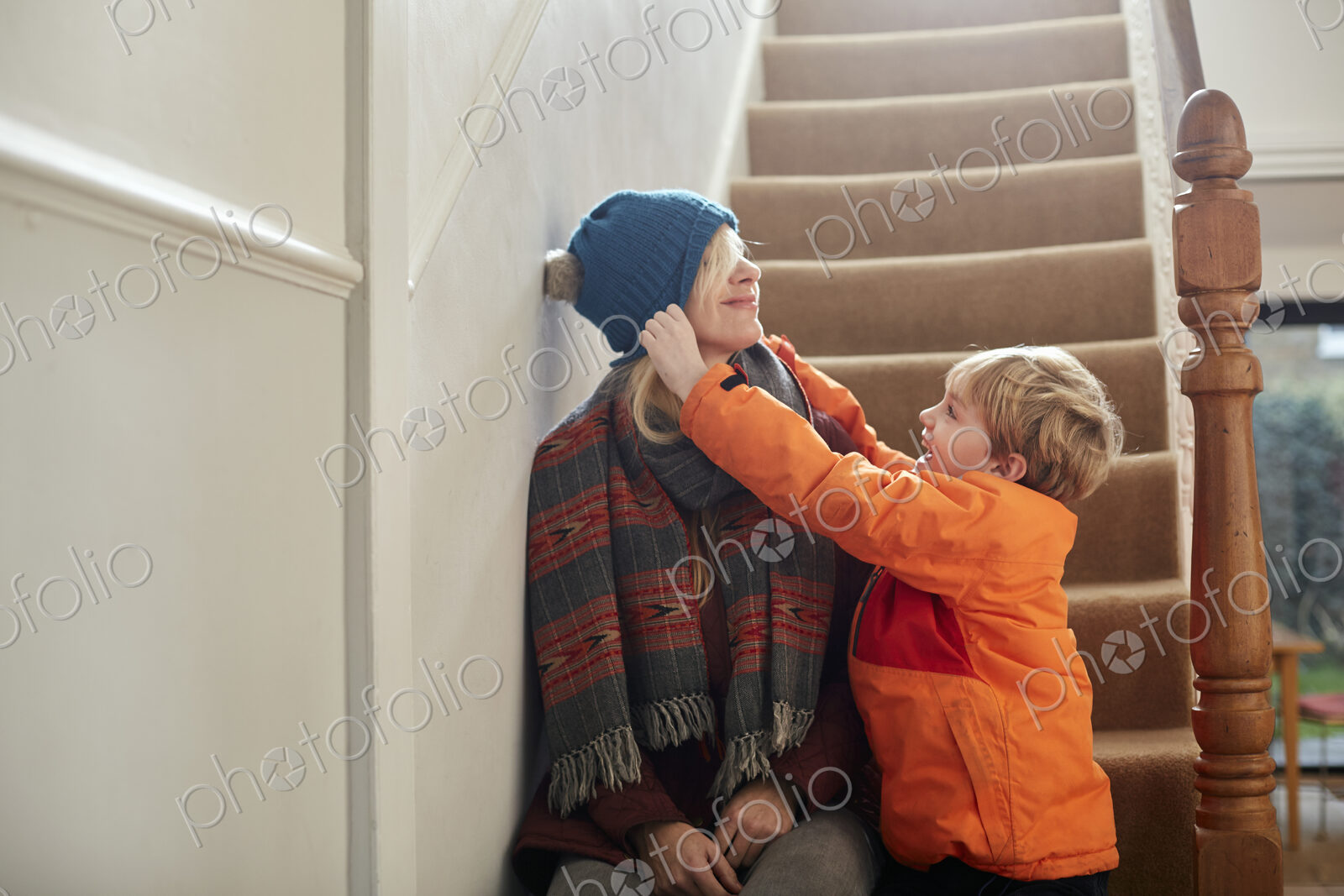 A boy pulling a hat over his mother’s eyes.