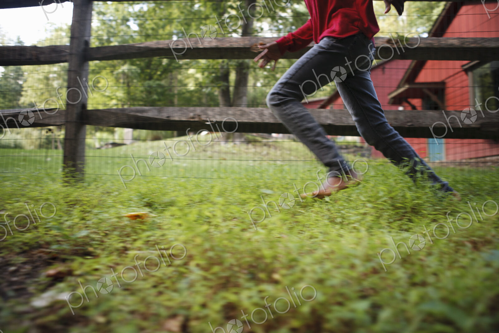 A boy running around a paddock fence outdoors.