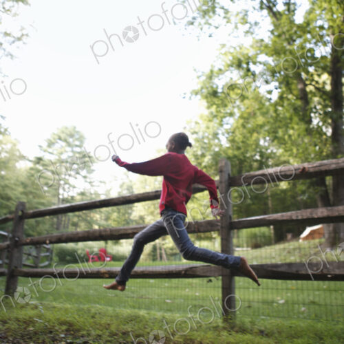 A boy running around a paddock fence outdoors. A boy running around a paddock fence outdoors.