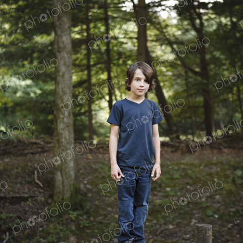 A boy standing on a narrow tree trunk, balancing and walking the plank. A boy standing on a narrow tree trunk, balancing and walking the plank.