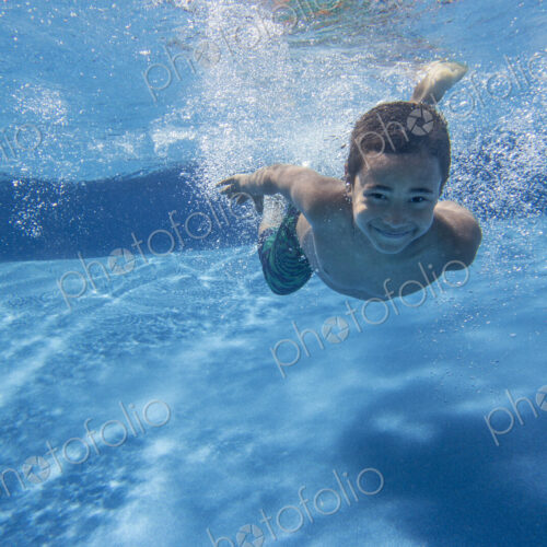A boy swimming underwater smiling at the camera. A boy swimming underwater smiling at the camera.