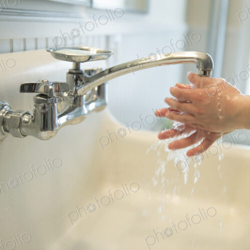 A boy washing his hands under the bathroom tap. A boy washing his hands under the bathroom tap.