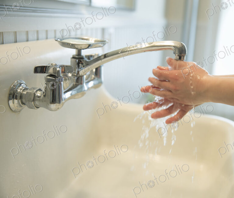 A boy washing his hands under the bathroom tap.