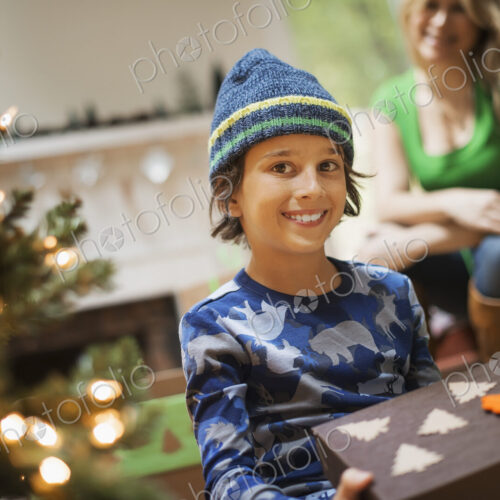 A boy with a Christmas present, gift wrapped in a box with recycled Christmas packaging. A boy with a Christmas present, gift wrapped in a box with recycled Christmas packaging.