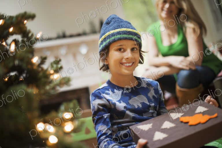 A boy with a Christmas present, gift wrapped in a box with recycled Christmas packaging.