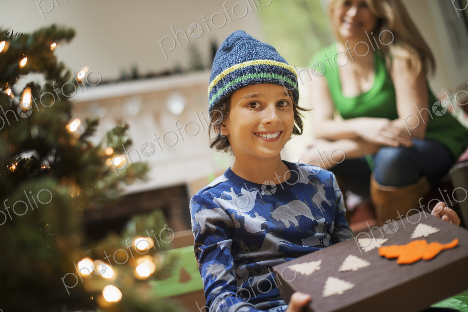A boy with a Christmas present, gift wrapped in a box with recycled Christmas packaging.