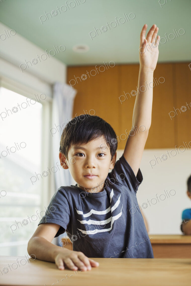 A boy with his hand up ready to answer a question.