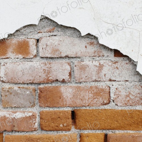 A brick wall and plasterwork flaking off.