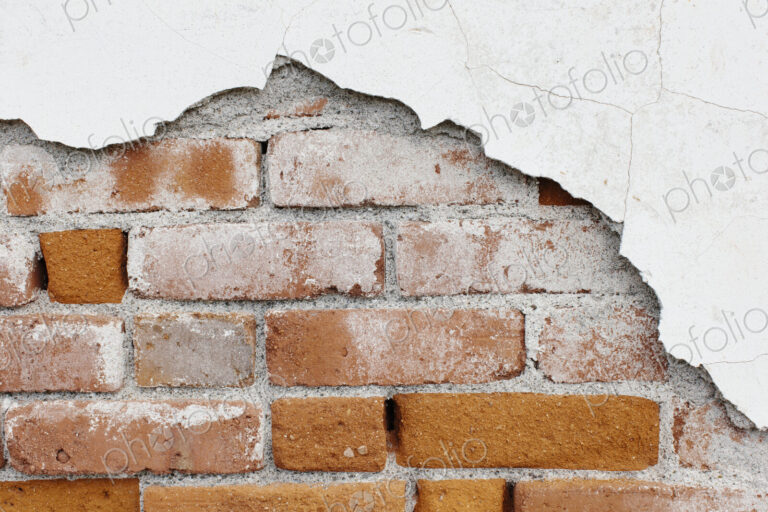 A brick wall and plasterwork flaking off.