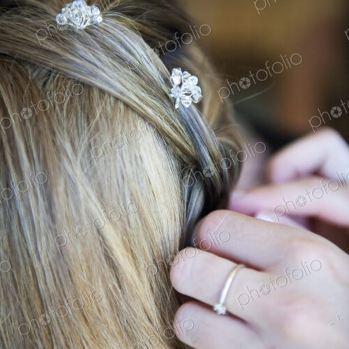 A bride having her hair braided and accessorized with hair pins.