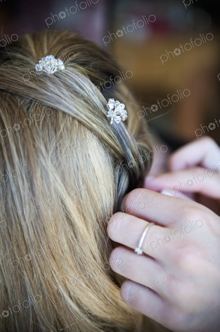 A bride having her hair braided and accessorized with hair pins.