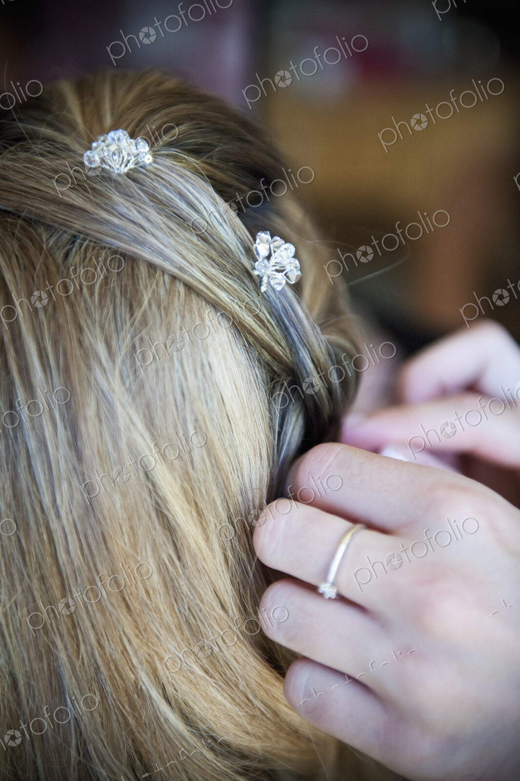 A bride having her hair braided and accessorized with hair pins.