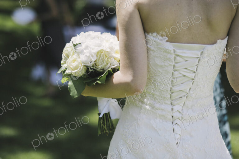 A bride in a fitted bodice, white dress with lacings across the fitted back panels.
