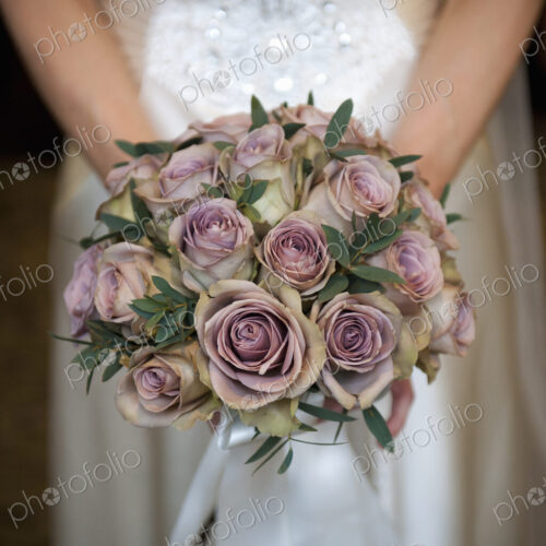 A bride in a white dress, holding a bridal bouquet of pastel coloured roses. A bride in a white dress, holding a bridal bouquet of pastel coloured roses.