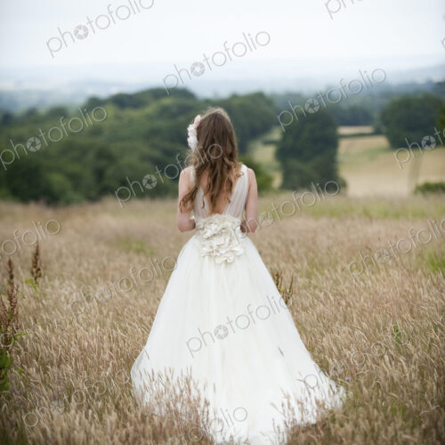 A bride in her wedding dress standing in a field. A bride in her wedding dress standing in a field.