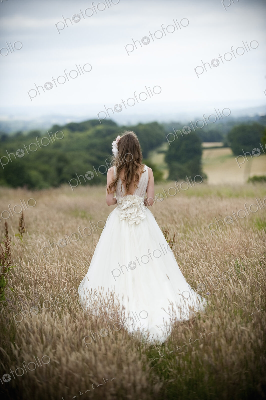 A bride in her wedding dress standing in a field.